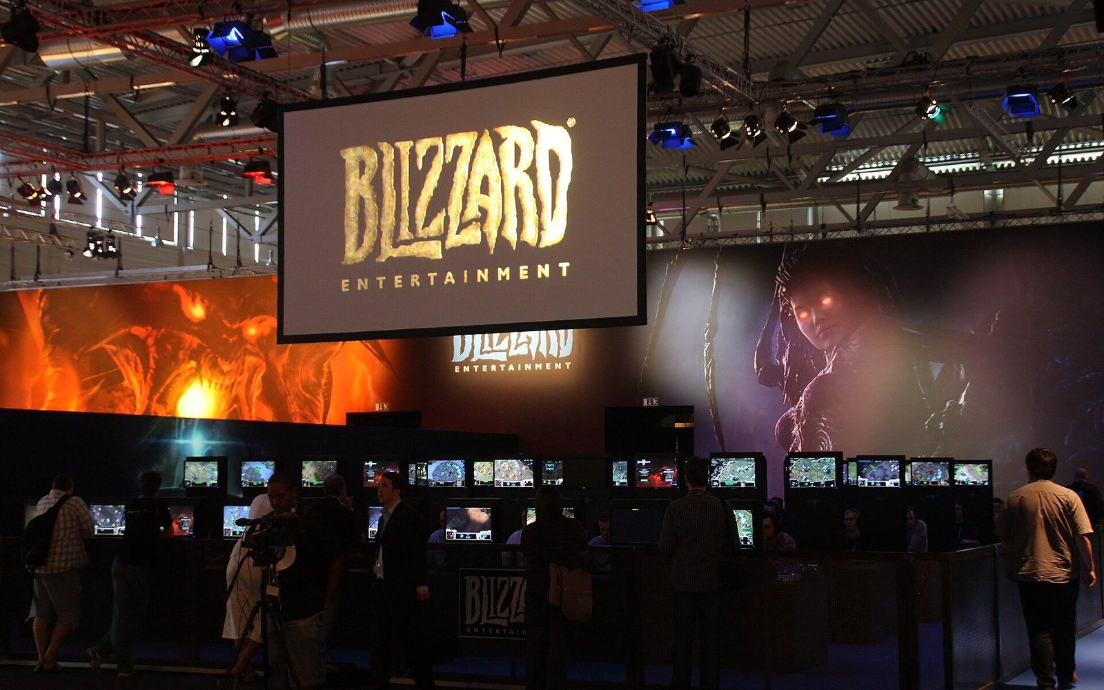 Attendees browse gaming stations beneath a large Blizzard Entertainment sign at a convention booth