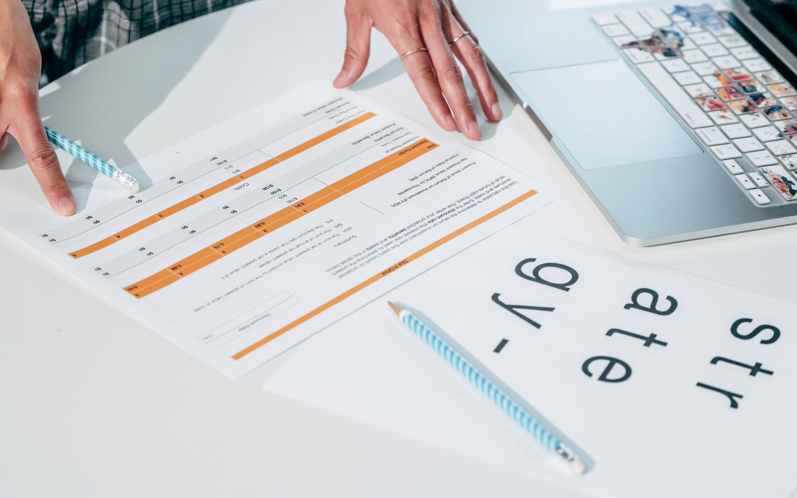 A printed quarterly earnings document open on a desk at the segment revenue table, a hand resting beside it, pen nearby